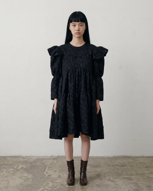 Tatum jacquard dress in black featuring a structured floral-patterned fabric, high-neck detail, and a voluminous skirt.