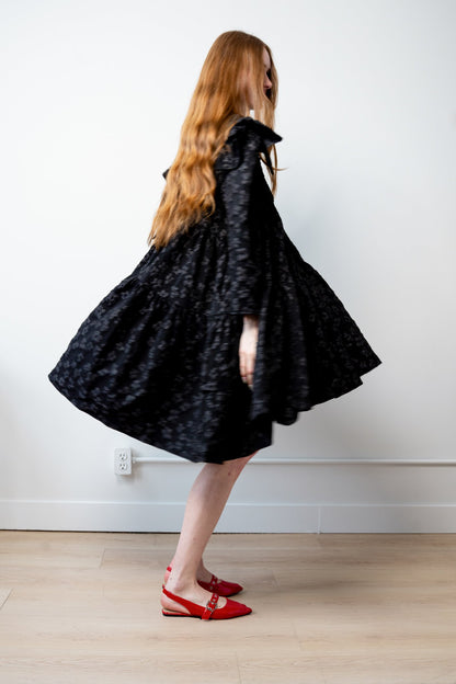 Side of Tatum jacquard dress in black featuring structured floral-patterned fabric, high-neck detail, and a voluminous skirt.